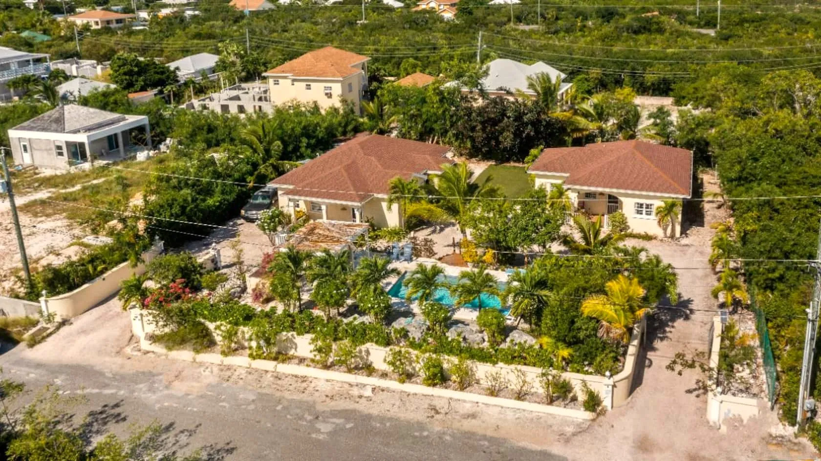 Aerial view of the walled two-villa compound with the shared pool and tropical gardens between the houses
