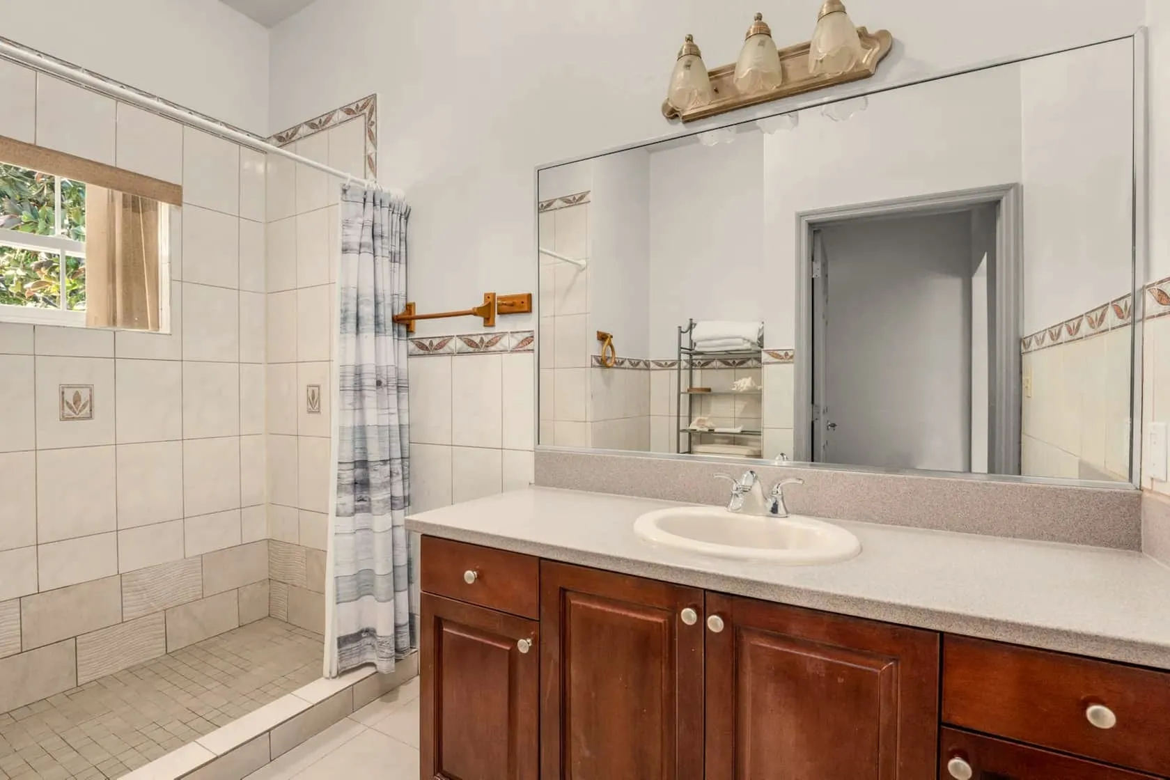 Bright bathroom with walk-in tiled shower and wide granite-look vanity