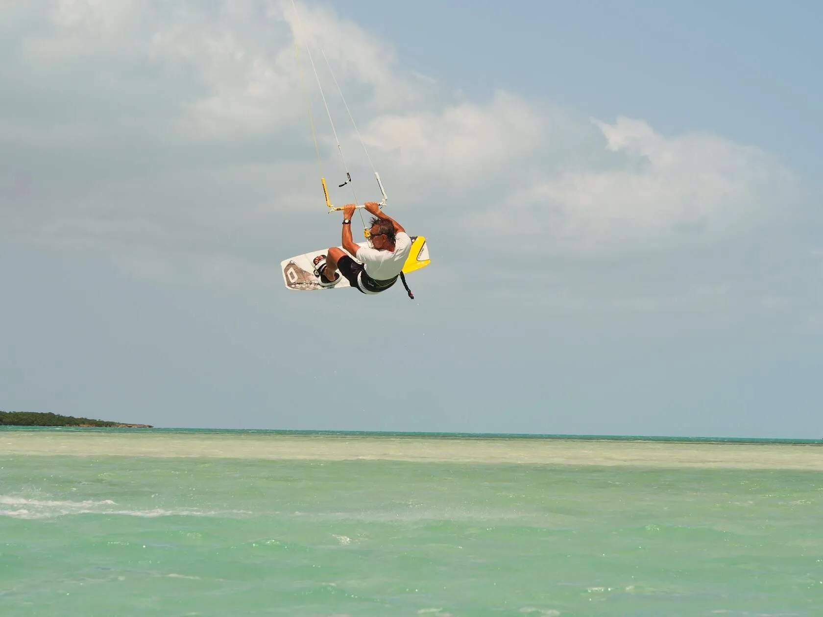 Kiteboarder catching air over the shallow turquoise flats off Long Bay