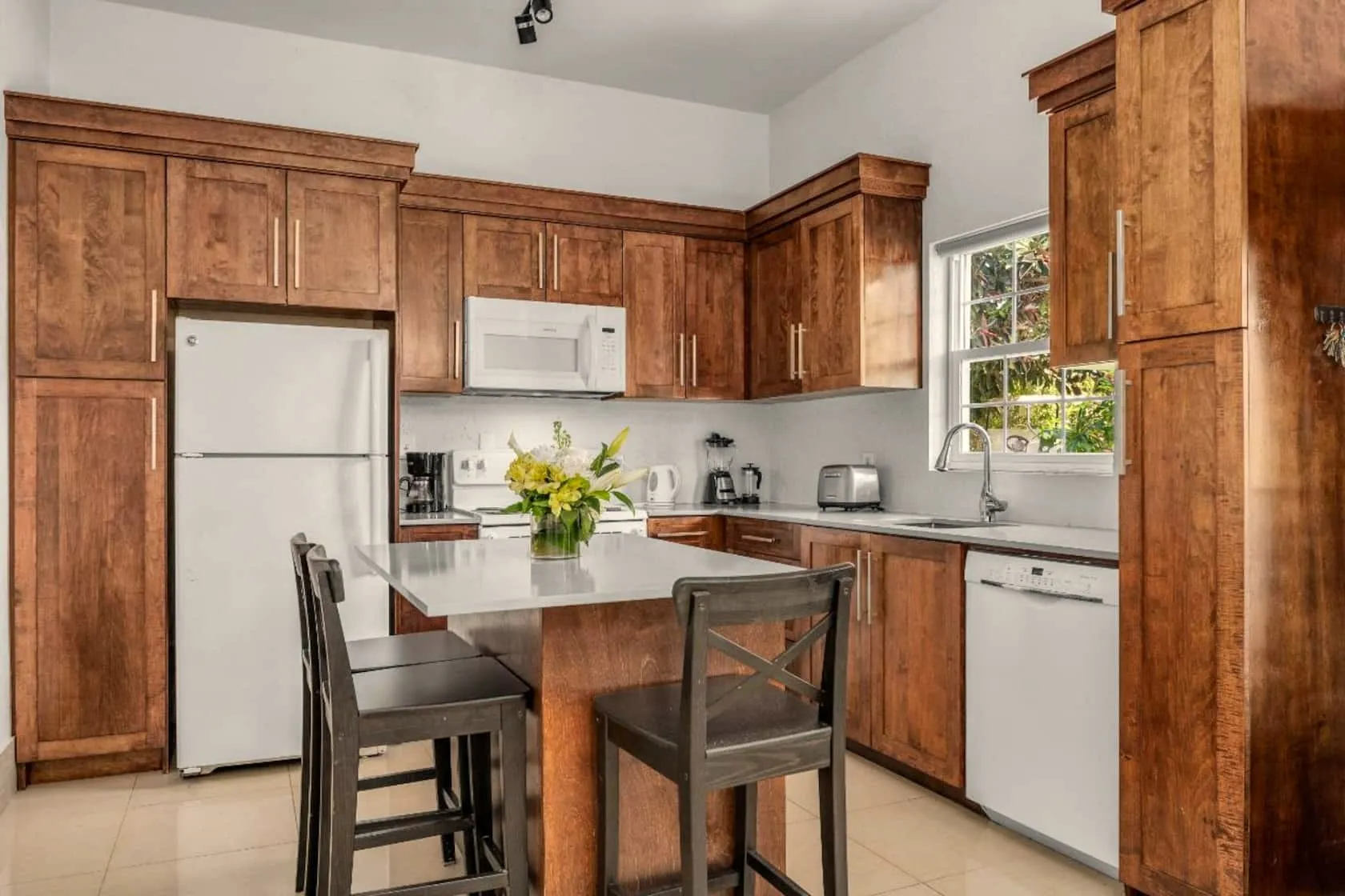 Bright full kitchen with wood shaker cabinetry, white appliances, and an island with bar seating