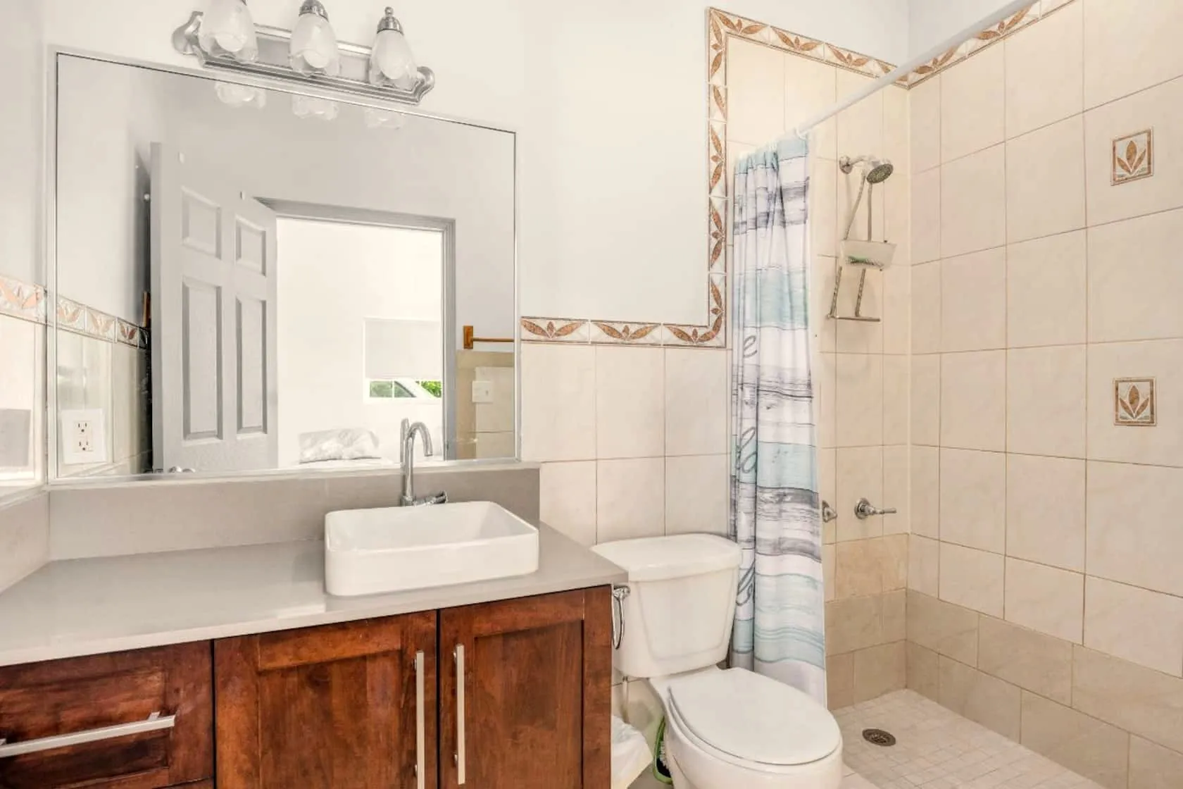 Bright bathroom with vessel sink, wood vanity, and walk-in tiled shower