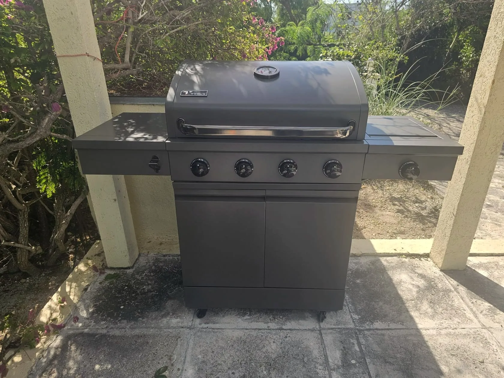 Gas grill on the covered patio, framed by bougainvillea and greenery